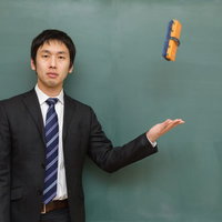 黒板消しを片手で投げるポーズの塾の講師の写真
