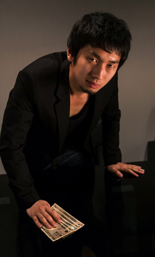 テーブルに紙幣を叩きつけて睨みつけるブローカー風の男性