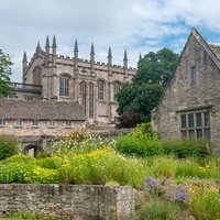 赤い花壇と芝生に囲まれたクライストチャーチの石造りの建物の写真