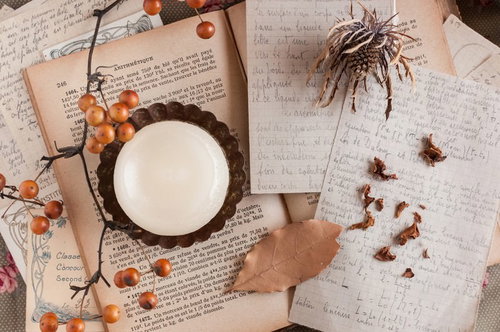 ロウソクの灯りに照らされた古い本や瓶が並ぶ魔女の机