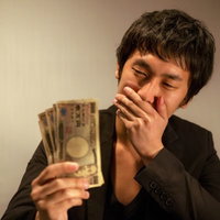 報酬を手に入れ、「うわっ・・・こんなに！」と口に手を当て驚く男性の写真