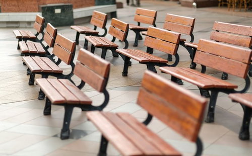 公園の木陰にきれいに等間隔で並んだ木製ベンチ