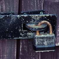 錆が浮いて年月を感じる古びた南京錠の接写の写真