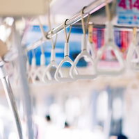 通勤電車の車内に並ぶ銀色のつり革の列の写真