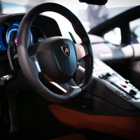 ランボルギーニ・アヴェンタドールの運転席でハンドル操作する高級車の写真