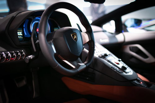 ランボルギーニ・アヴェンタドールの運転席でハンドル操作する高級車