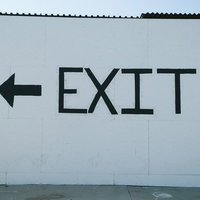 EXIT（お帰りはあちら）と左向き矢印の出口案内サインの写真