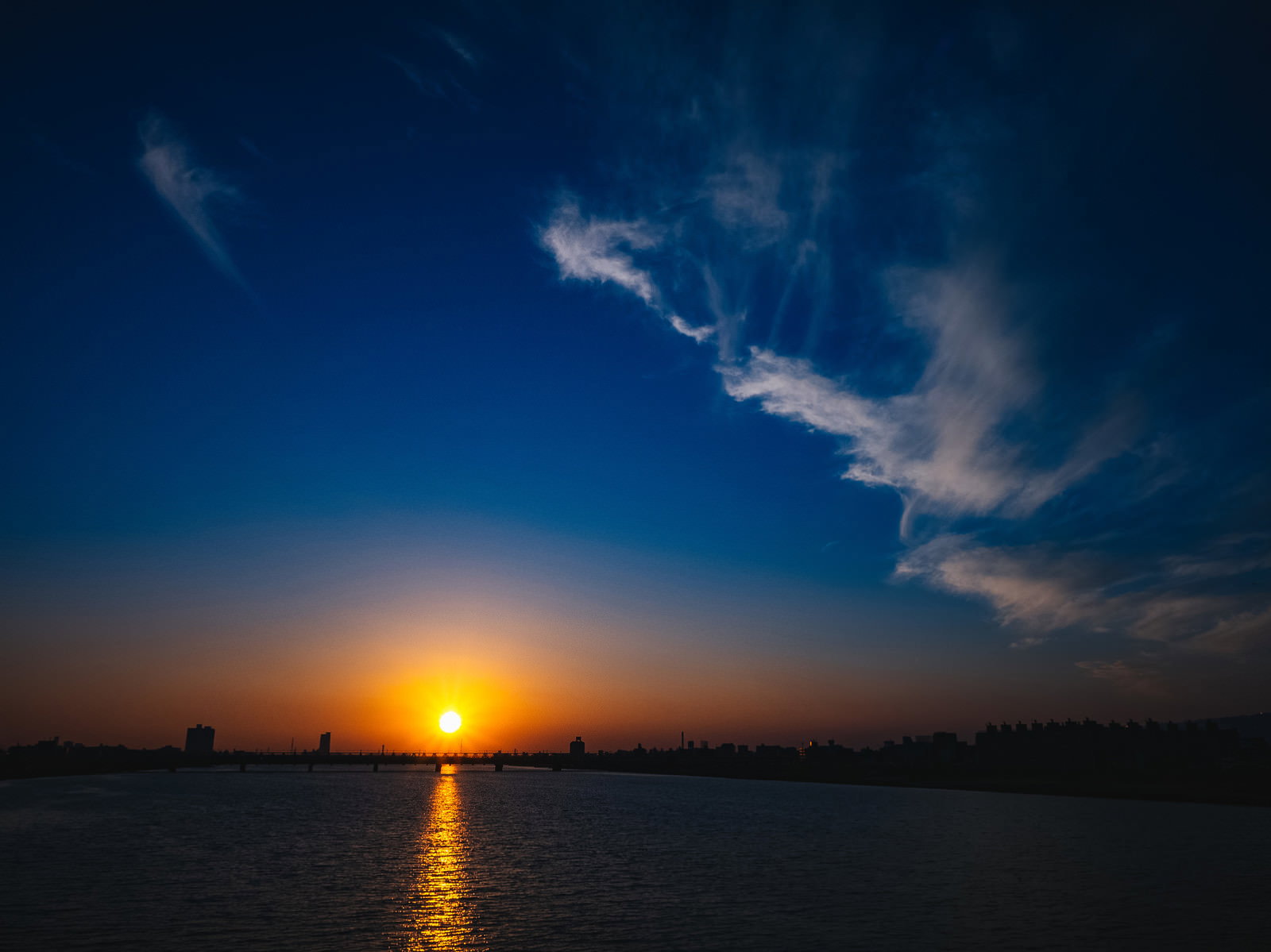 水面にオレンジ色の夕日が反射する夕暮れの風景