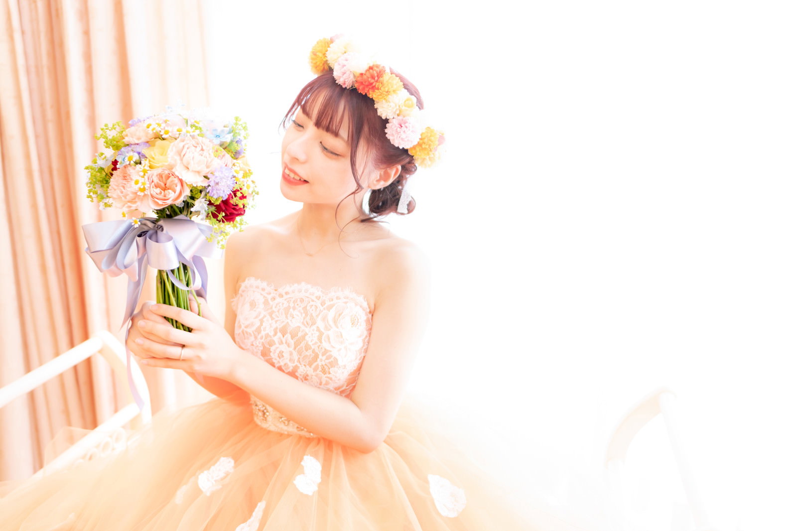 純白のウェディングドレスを着た新婦がブーケを両手で持っている［モデル：高尾実生］