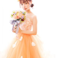 オレンジ色のウェディングドレス姿で花を持つ花嫁の写真