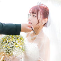 手鏡を見ながら化粧直しをする花嫁のウェディングドレス姿の写真