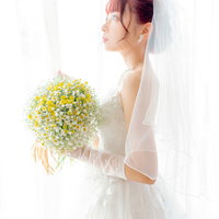 白いウェディングドレス姿で黄色いブーケを持つ花嫁の写真