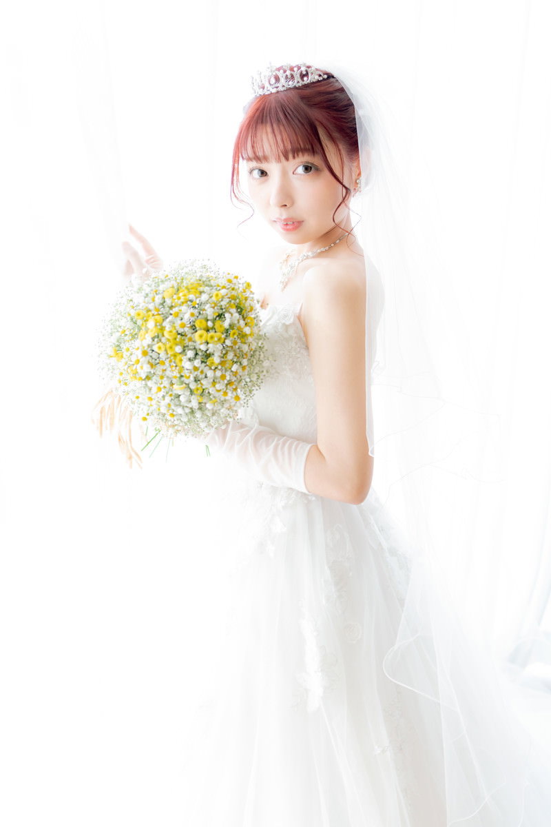 白いウェディングドレスを着て黄色い花のブーケを持つ花嫁［モデル：高尾実生］