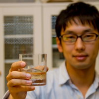 バーカウンターでグラスを持って乾杯する笑顔の男性の写真