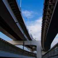 橋脚と鉄骨が頭上に広がるレインボーブリッジ高速道路の下の写真