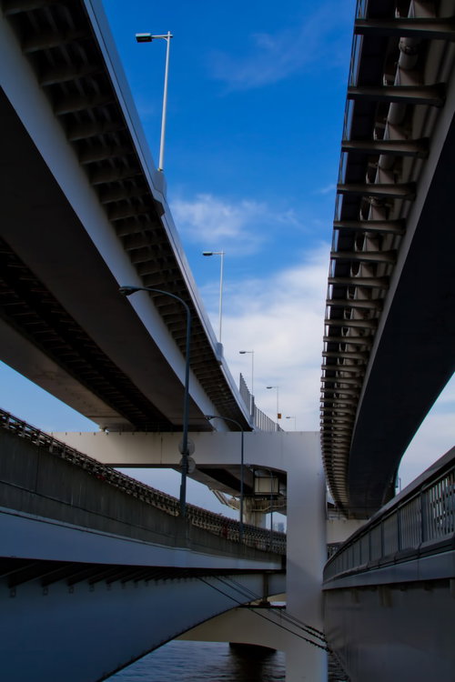 橋脚と鉄骨が頭上に広がるレインボーブリッジ高速道路の下