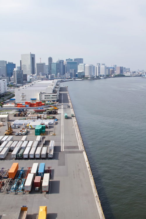 港に並ぶコンテナと背景のビル群の風景