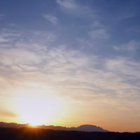 青からオレンジに変わるグラデーションの日没前の山なみの写真