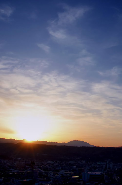 青からオレンジに変わるグラデーションの日没前の山なみ