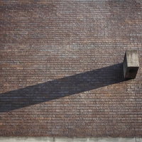 レンガの壁に伸びたブロックと煙突の影の写真