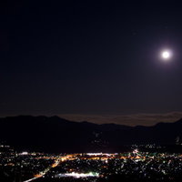 暗い夜空に浮かぶ街の灯と見下ろす満月の写真