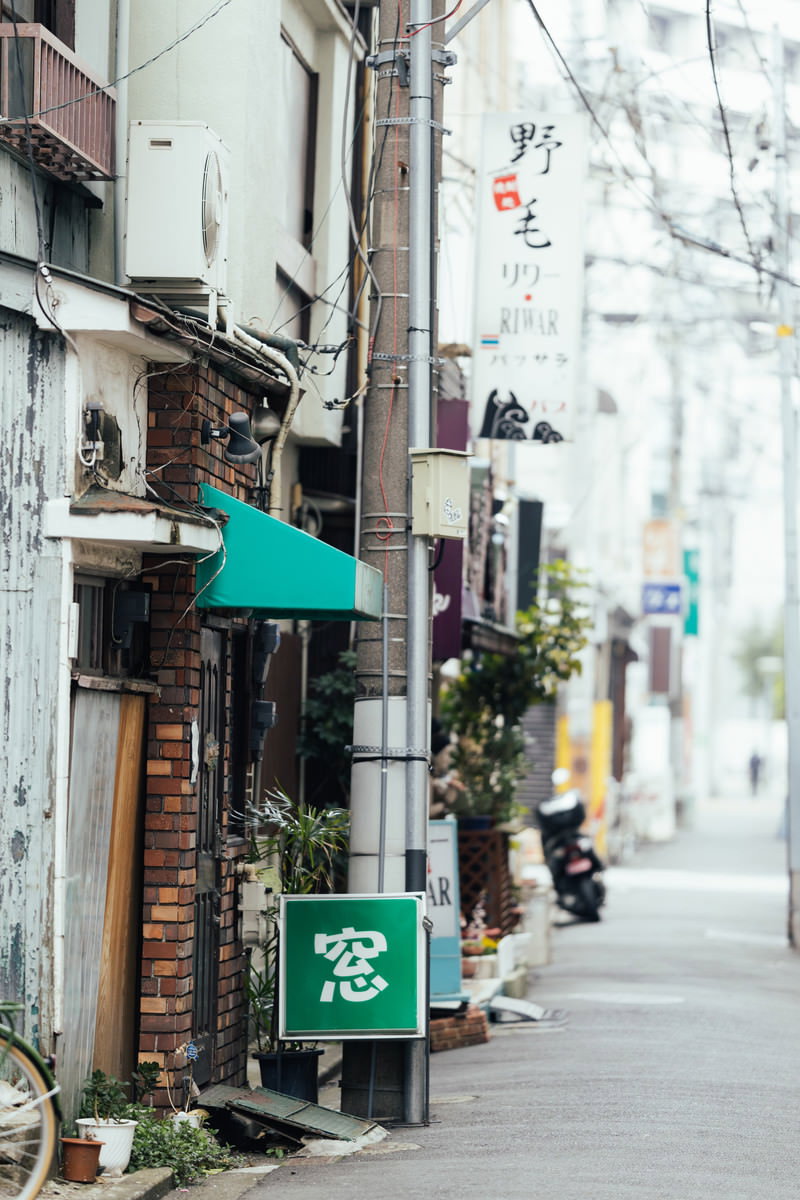 野毛の路地裏に緑色の看板やレンガ壁の飲食店が並ぶ昼間の風景