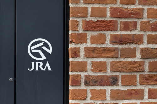 レンガの壁に映るJRAのロゴマーク、日本中央競馬会の公式マーク