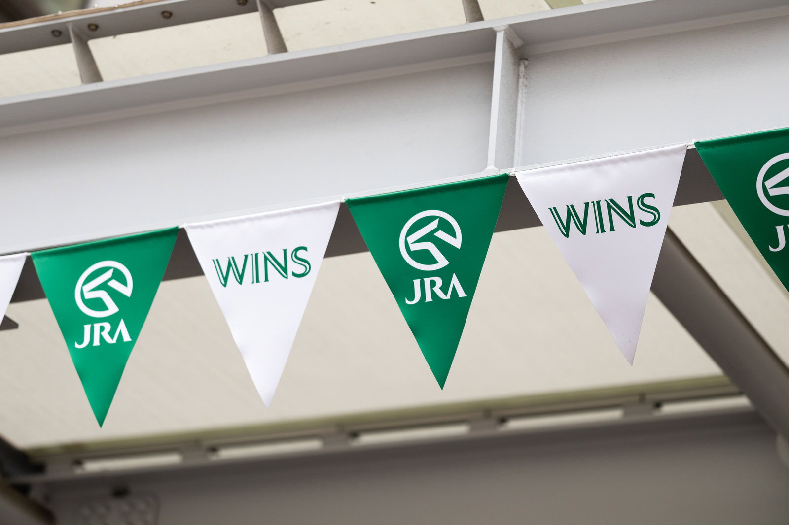 緑色の三角形の旗にWINSとJRAのロゴが印刷されて掲示されている様子