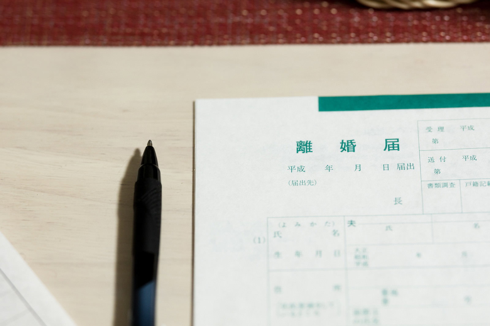 離婚届の用紙と黒い万年筆が机の上に置かれている様子