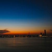 静寂な朝焼けと夜景が映る港町のシルエットの写真