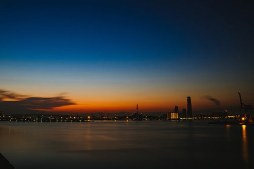 静寂な朝焼けと夜景が映る港町のシルエット