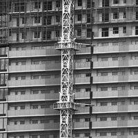 建設中の高層ビルとクレーンのモノクロの写真