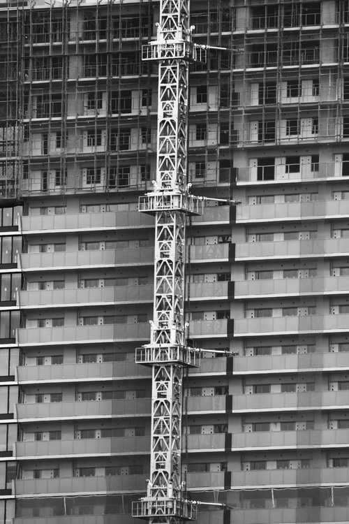 建設中の高層ビルとクレーンのモノクロ