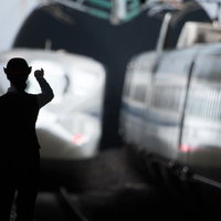 出発進行、駅員が手旗で新幹線を見送る瞬間の写真