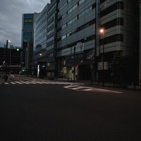 早朝の薄暗い秋葉原の車道とビル群、夜明け前の静寂の街並みの写真