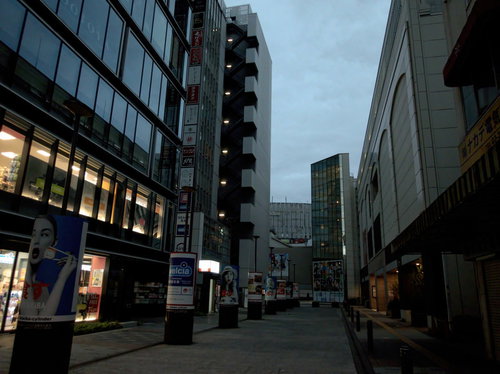 早朝の薄暗い秋葉原の路地裏、高いビルに囲まれた静寂の街