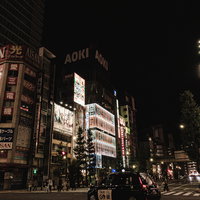 交差点を走るタクシーと光る高層ビルが立ち並ぶ夜の秋葉原の写真