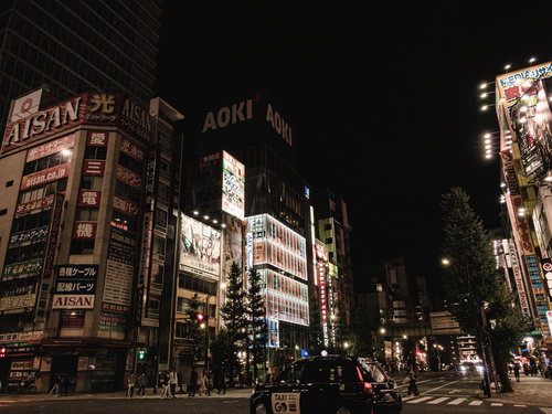交差点を走るタクシーと光る高層ビルが立ち並ぶ夜の秋葉原