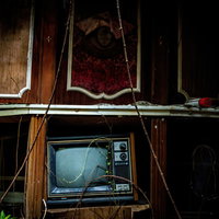 廃モーテルの薄暗い室内に置かれた映らないブラウン管テレビの写真