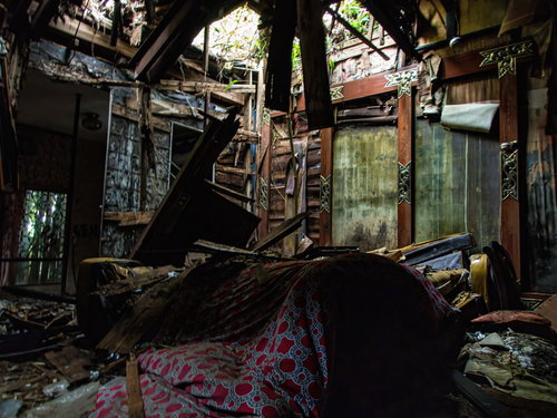 瓦礫が散乱する崩落した廃モーテルの天井と室内全体の荒廃した状態