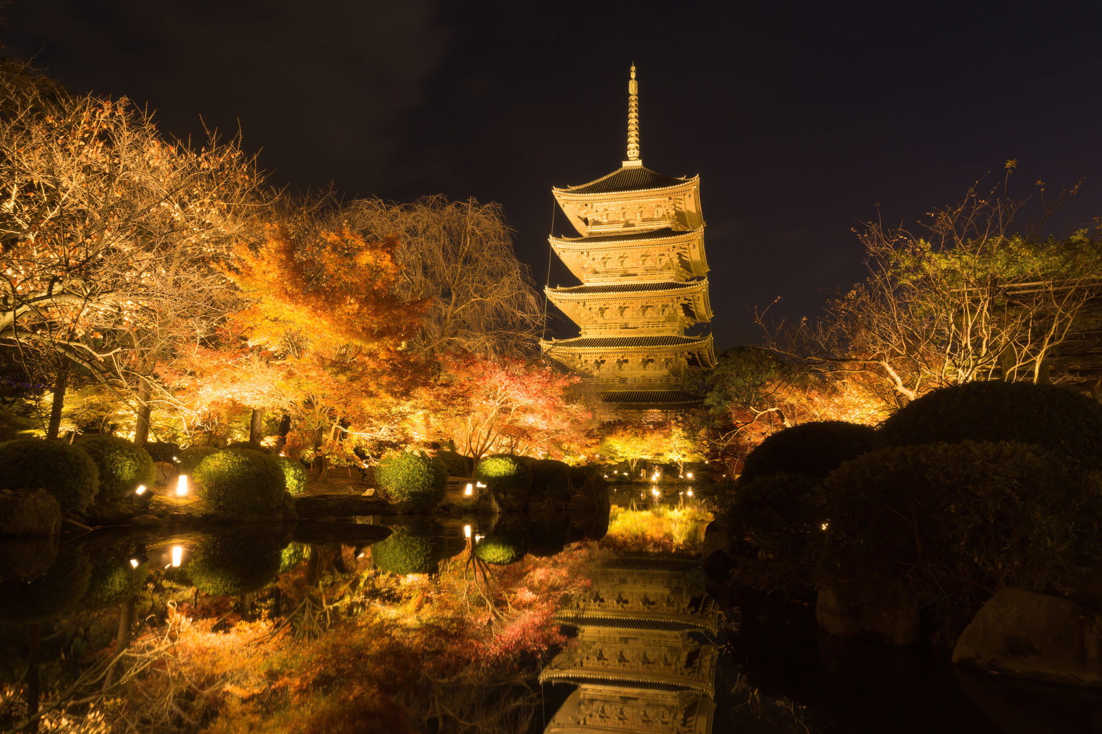 夜の東寺境内でライトアップされた五重塔と紅葉、池に映る水鏡