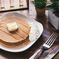 シロップがたっぷりかかったホットケーキとバターの写真