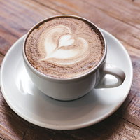 木目調のテーブルに置かれた白いカップのハート型ラテアートの写真