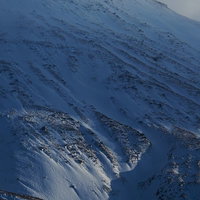 岩肌が露出した雪に覆われた冬の山の写真