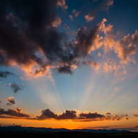 夕焼け空に広がる雲と放射状の光の写真