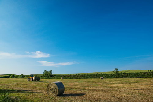 広大な農地の牧草ロールとトラクター