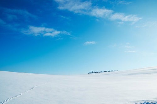 足跡が続く雪原と青空の冬景色