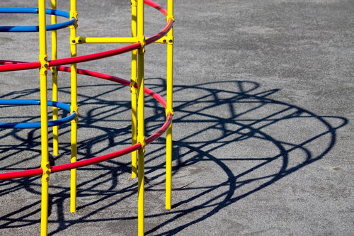 赤と青の横棒が付いた黄色い金属フレームのジャングルジム