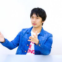 青いジャケットで両手を広げて説明するろくろ系男子の写真