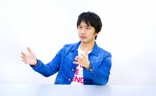 青いジャケットで両手を広げて説明するろくろ系男子